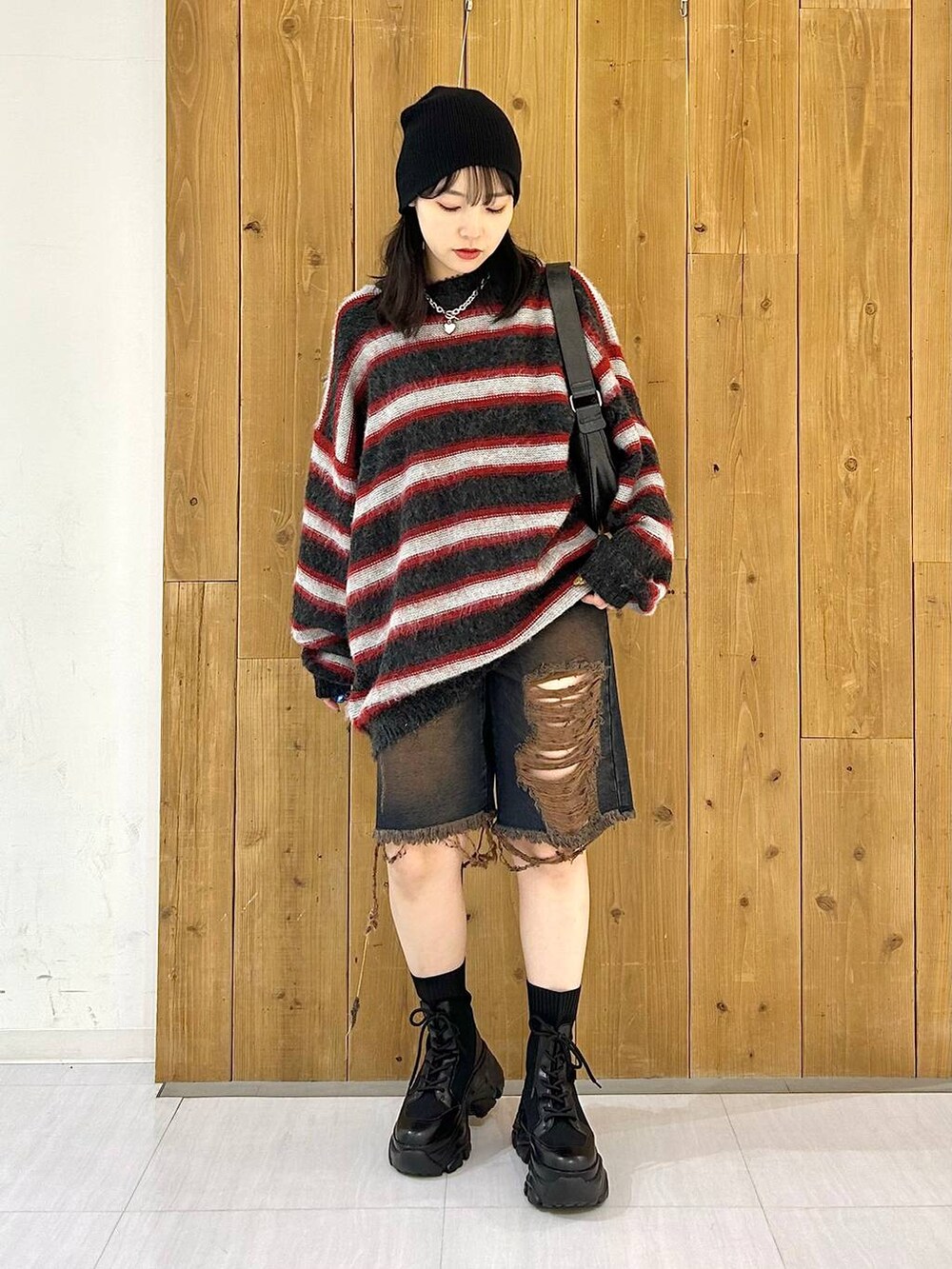 ブラック系のショルダーバッグ、ブラック系のブーツ、レッド系のニット/セーターを着用したレディースの秋コーディネートの8枚目の写真