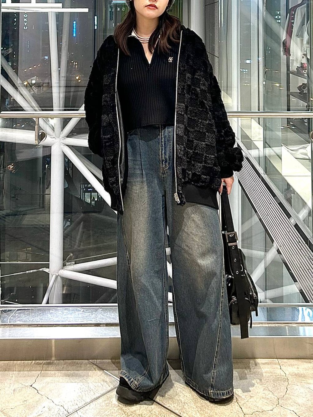 ブルー系のデニムパンツ、ブラック系のブルゾン、ブラック系のショルダーバッグを着用したレディースの秋コーディネートの3枚目の写真