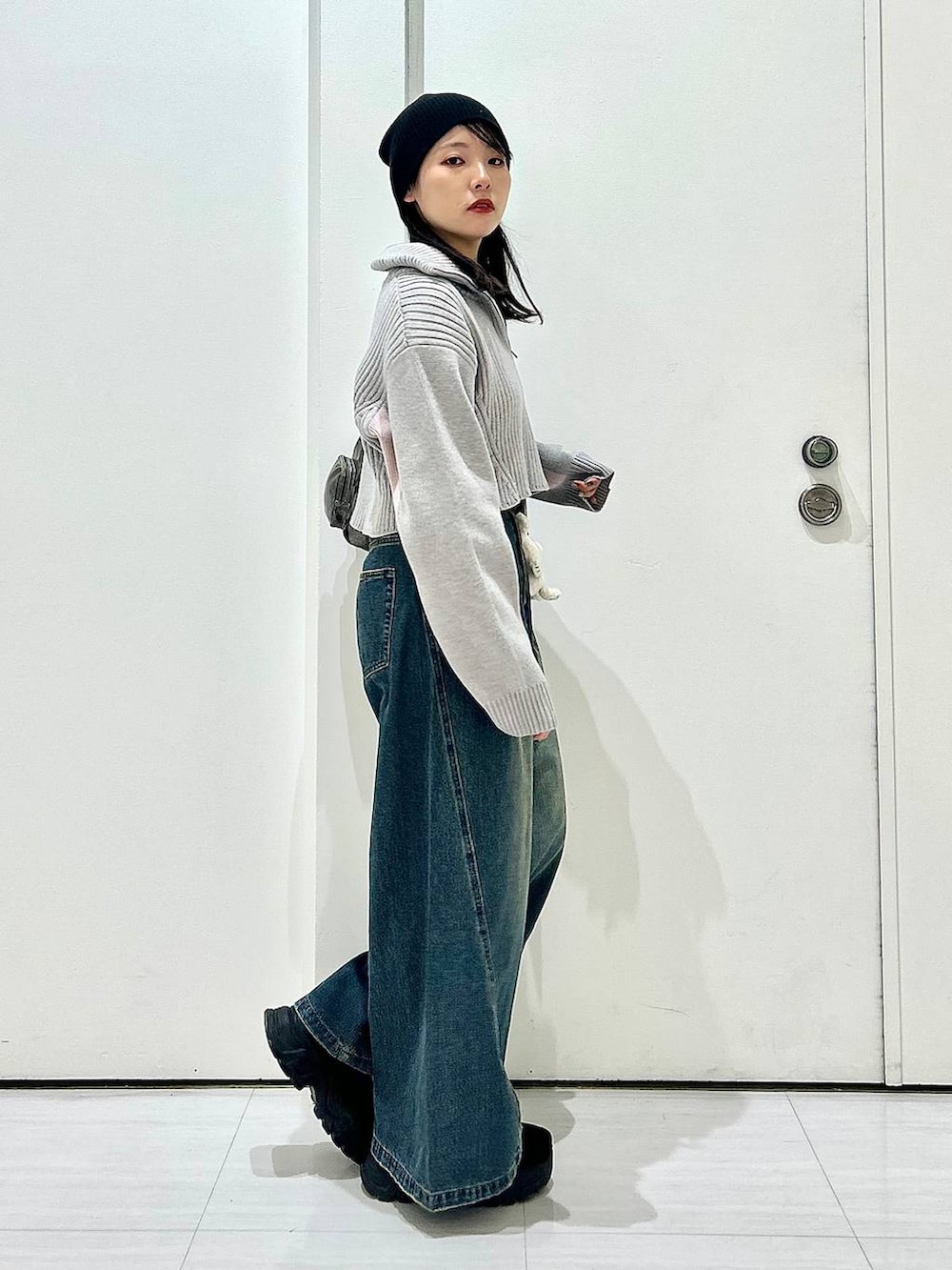 ブルー系のデニムパンツ、グレー系のショルダーバッグ、グレー系のニット/セーターを着用したレディースの秋コーディネートの5枚目の写真