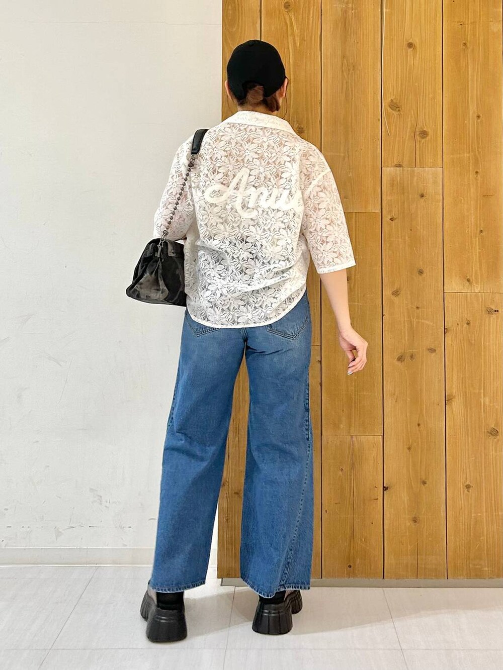 ブラック系のスニーカー、ブルー系のデニムパンツ、ホワイト系のシャツ/ブラウスを着用したレディースの春コーディネートの4枚目の写真