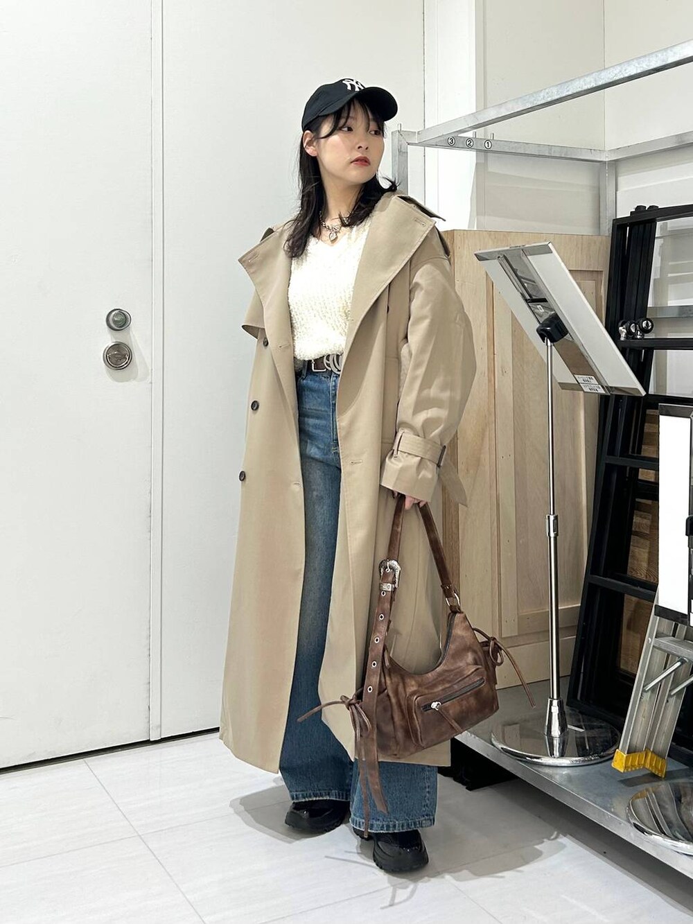 ブルー系のデニムパンツ、ブラウン系のショルダーバッグ、ベージュ系のトレンチコートを着用したレディースの冬コーディネートの5枚目の写真
