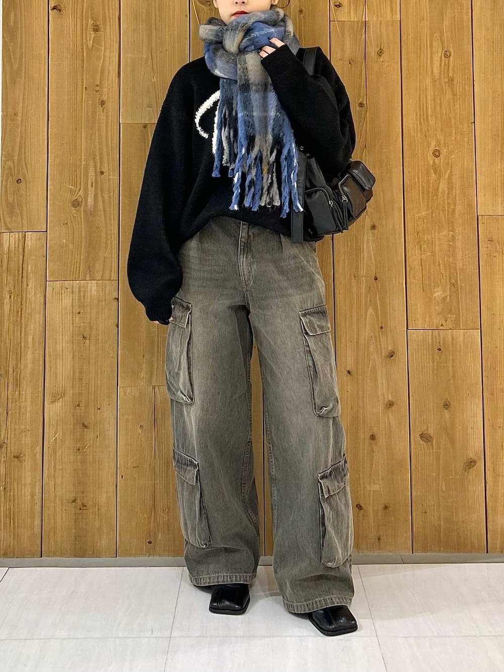 ブラック系のショルダーバッグ、ブラック系のニット/セーター、ブラック系のデニムパンツを着用したレディースの冬コーディネートの2枚目の写真