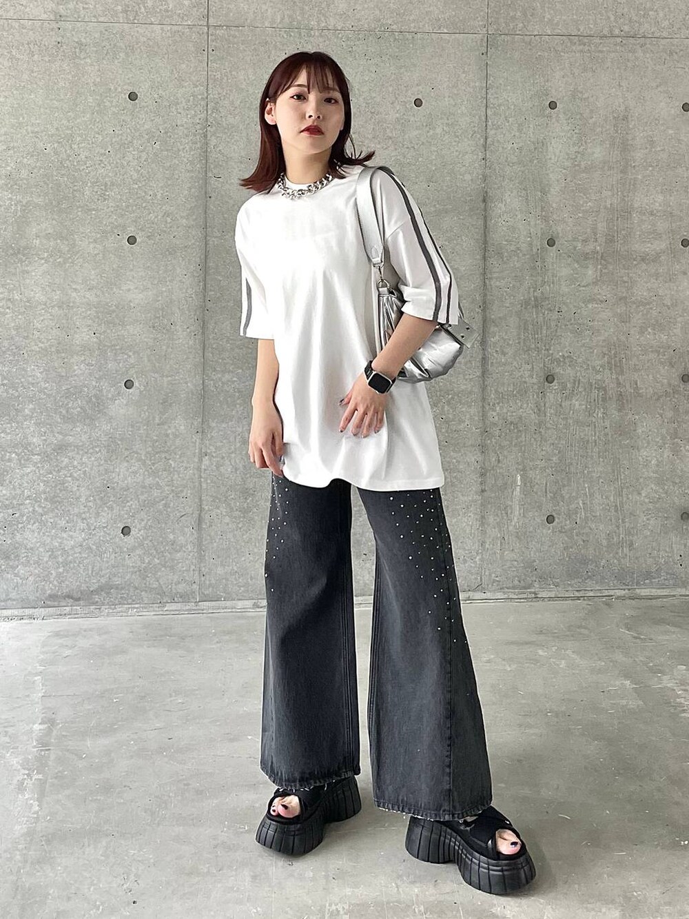 ブラック系のスニーカー、ホワイト系のTシャツ/カットソー、ブラック系のデニムパンツを着用したレディースの春コーディネートの2枚目の写真