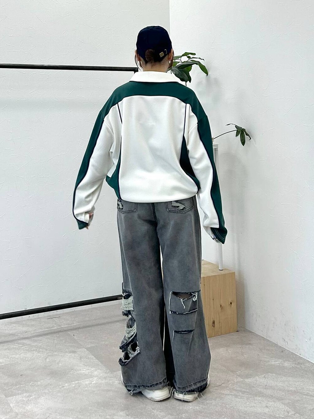 ホワイト系のポロシャツ、ブラック系のデニムパンツ、ブルー系のキャップを着用したレディースの冬コーディネートの6枚目の写真