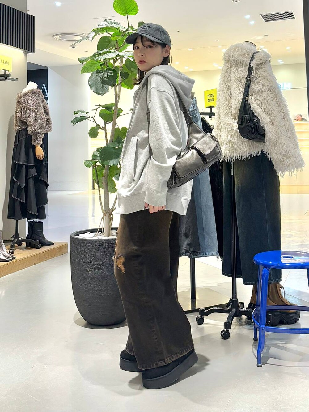 ブラック系のショルダーバッグ、グレー系のパーカー、ブラック系のブーツを着用したレディースの冬コーディネートの4枚目の写真