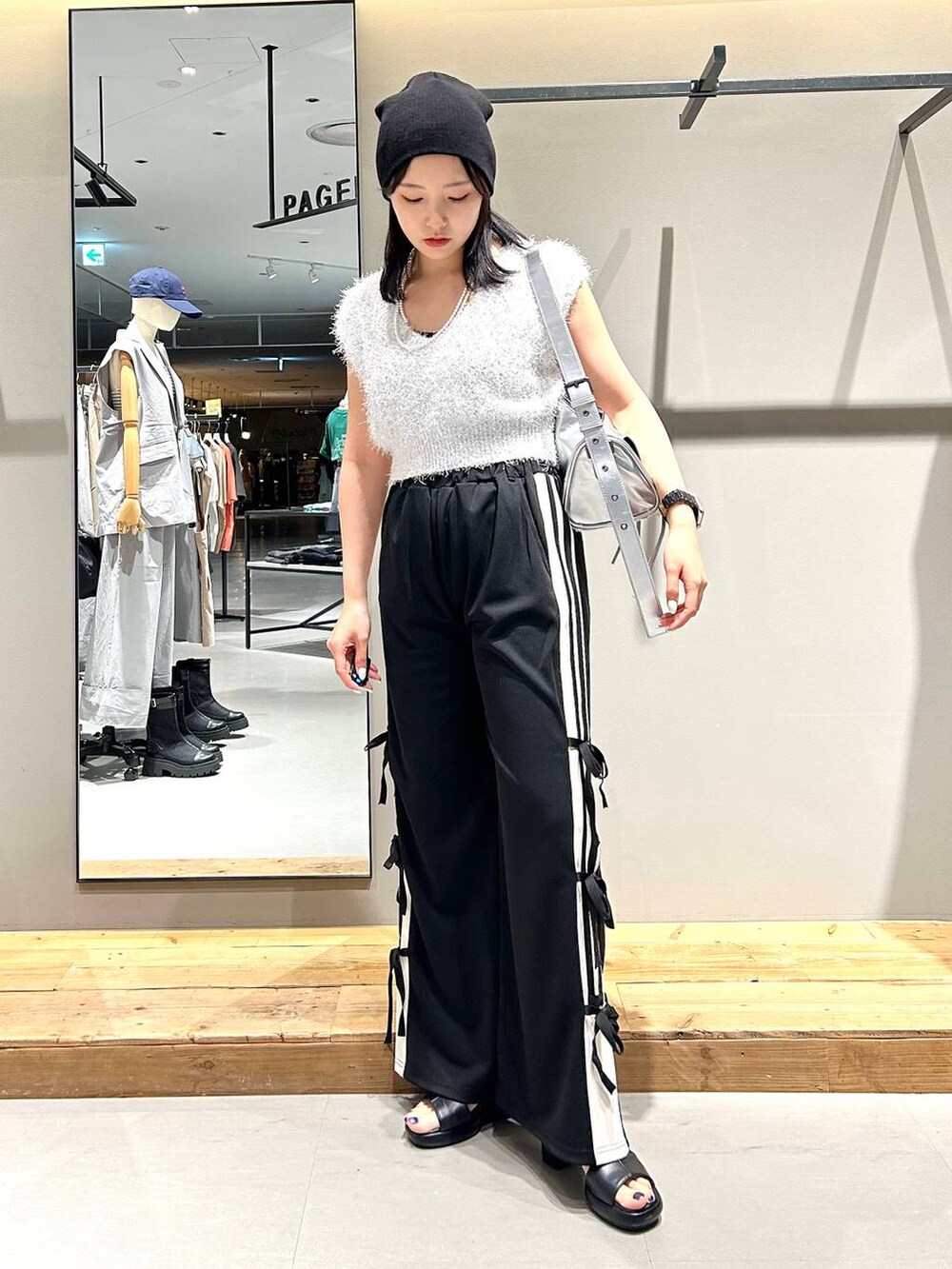 ブラック系のサンダル、ホワイト系のベスト、ブラック系のキャミソールを着用したレディースの夏コーディネートの6枚目の写真