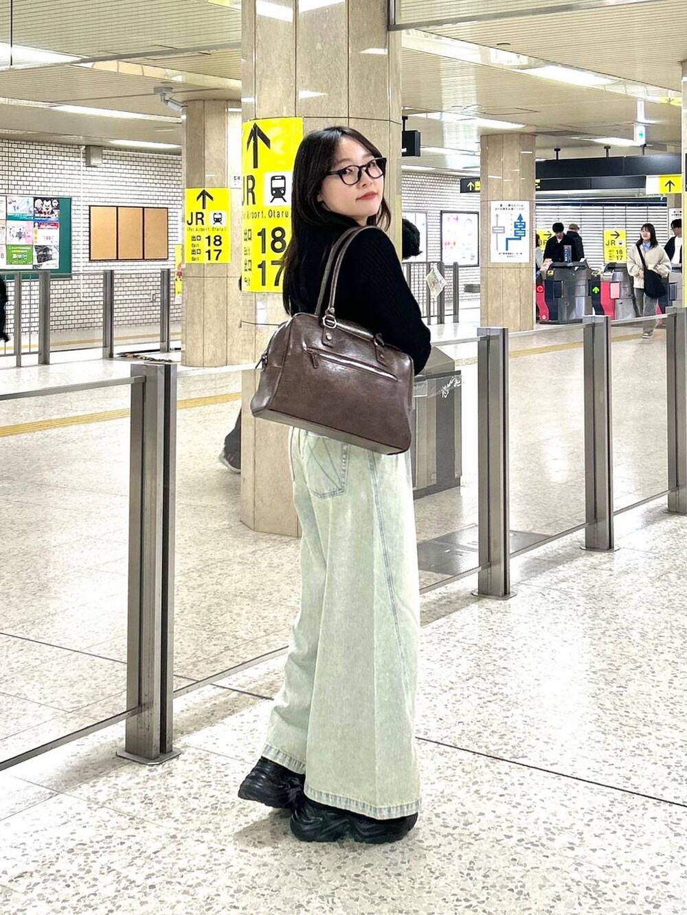 ブラック系のスニーカー、ブルー系のデニムパンツ、ブラウン系のボストンバッグを着用したレディースの夏コーディネートの3枚目の写真