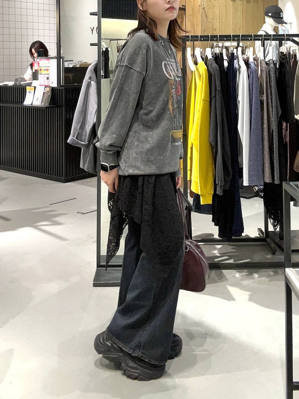 ブラック系のスニーカー、ブラック系のデニムパンツ、レッド系のボストンバッグを着用したレディースの秋コーディネートの5枚目の写真