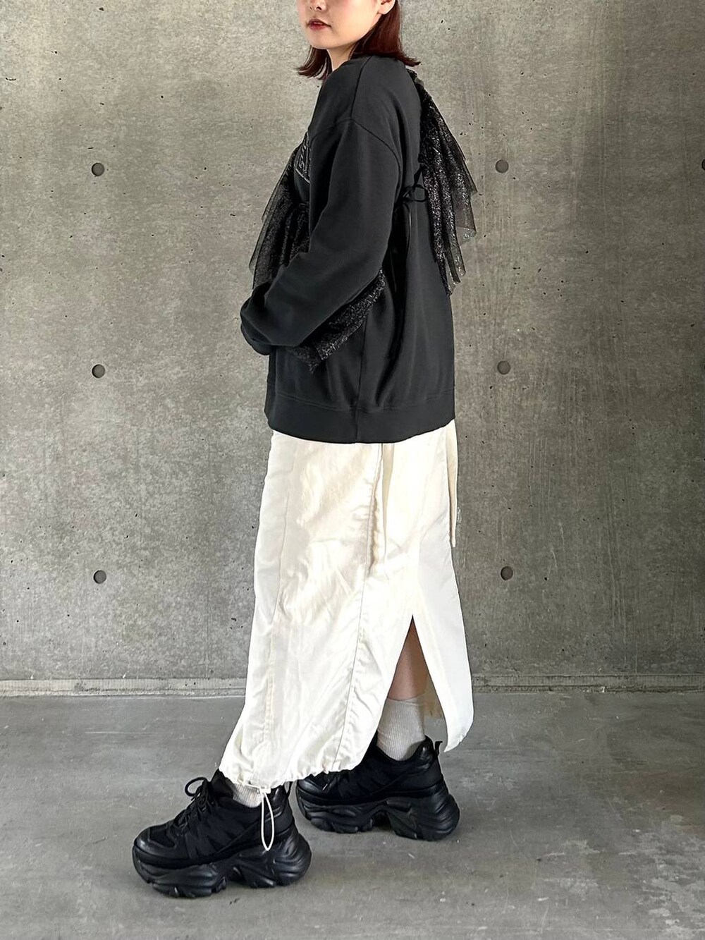 ブラック系のスニーカー、ホワイト系のスカート、ブラック系のスウェットを着用したレディースの春コーディネートの7枚目の写真