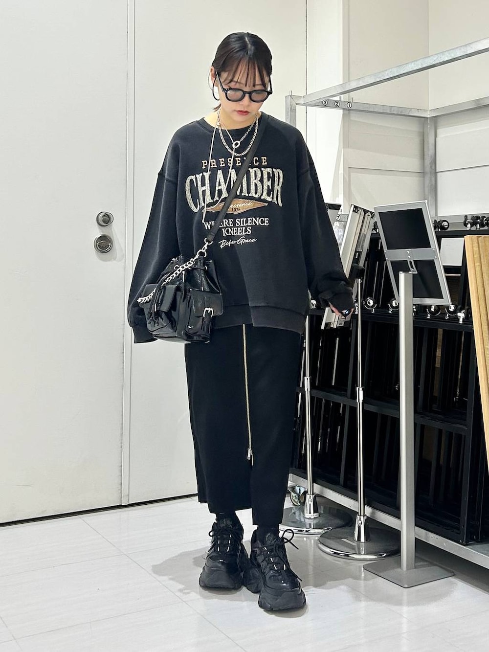 ブラック系のショルダーバッグ、グレー系のスウェット、ブラック系のスカートを着用したレディースの秋コーディネートの2枚目の写真