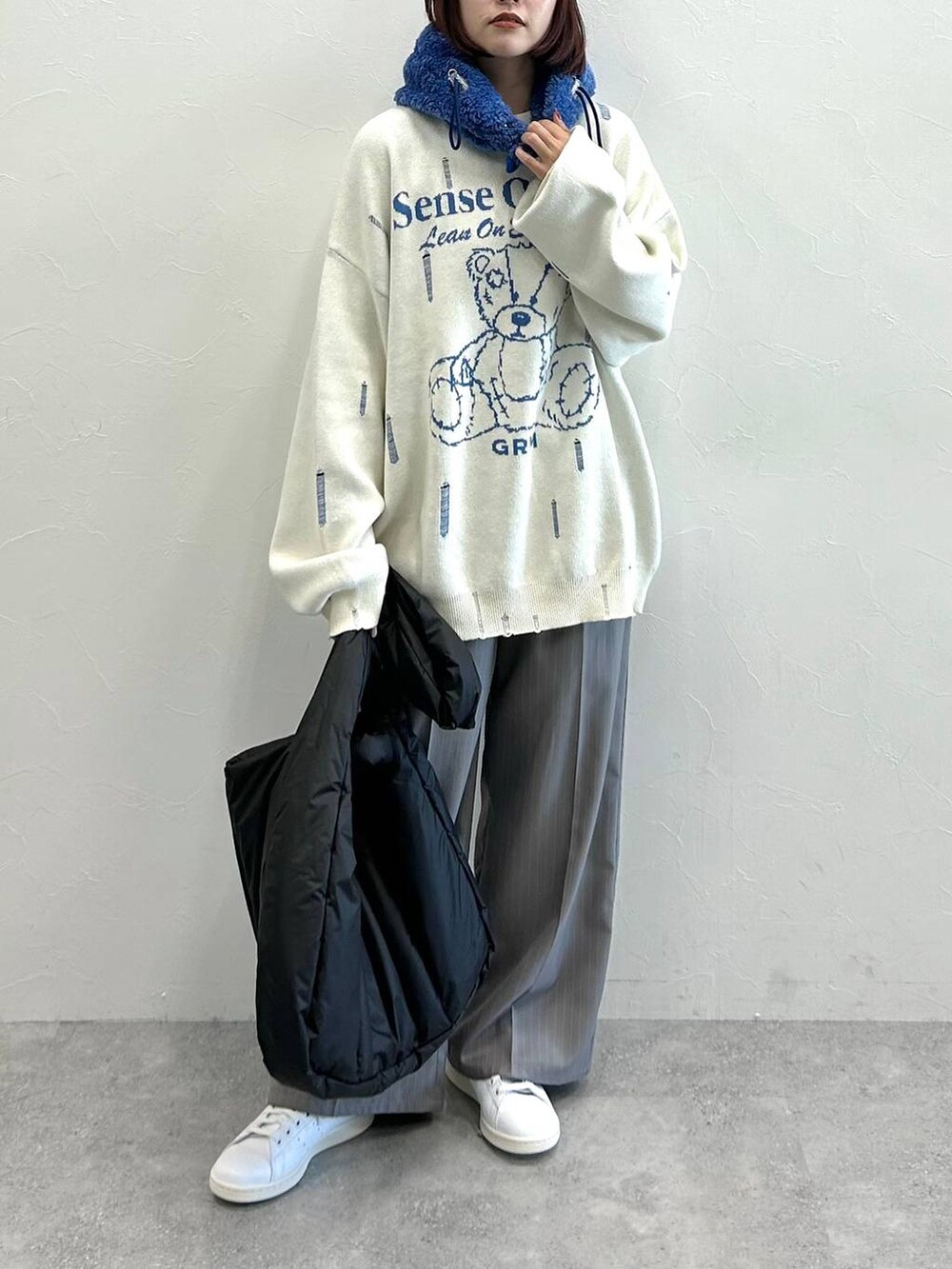 グレー系のスラックス、ホワイト系のニット/セーター、ブラック系のトートバッグを着用したレディースの秋コーディネートの3枚目の写真