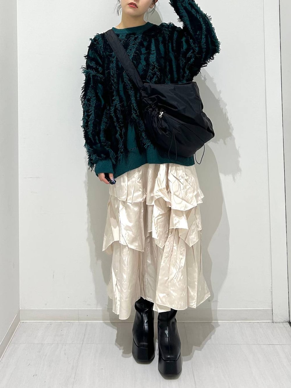 ベージュ系のスカート、ブラック系のブーツ、ブラック系のショルダーバッグを着用したレディースの秋コーディネートの2枚目の写真