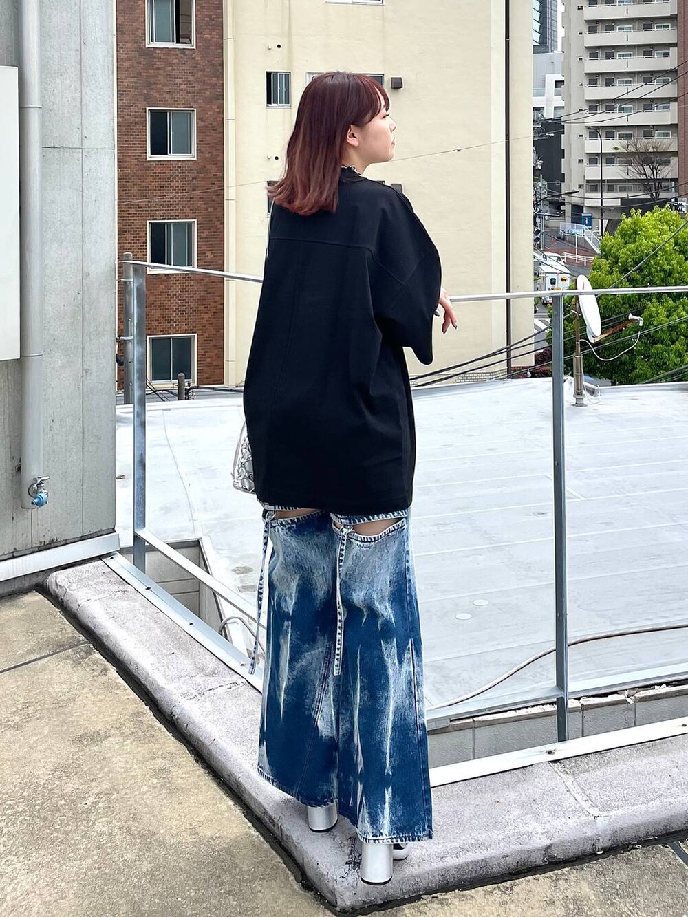 シルバー系のサンダル、シルバー系のショルダーバッグ、ブルー系のデニムパンツを着用したレディースの春コーディネートの6枚目の写真