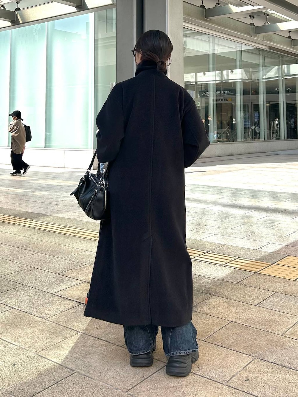 ブラック系のスニーカー、ブルー系のデニムパンツ、ブラック系のボストンバッグを着用したレディースの秋コーディネートの4枚目の写真