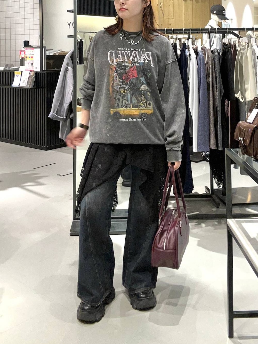 ブラック系のスニーカー、ブラック系のデニムパンツ、レッド系のボストンバッグを着用したレディースの秋コーディネートの2枚目の写真