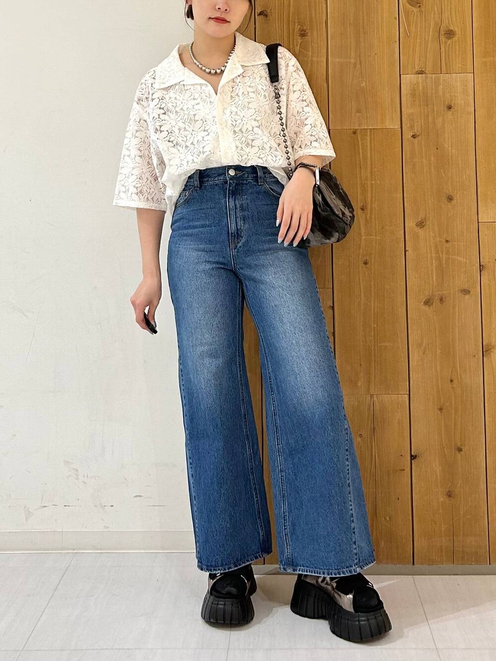 ブラック系のスニーカー、ブルー系のデニムパンツ、ホワイト系のシャツ/ブラウスを着用したレディースの春コーディネートの2枚目の写真
