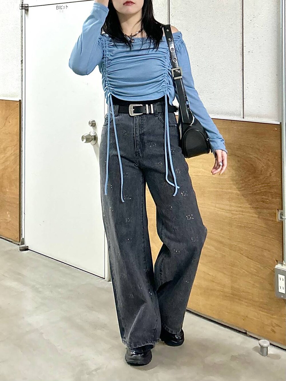 ブラック系のデニムパンツ、ブラック系のスニーカー、ブラック系のショルダーバッグを着用したレディースの春コーディネートの4枚目の写真