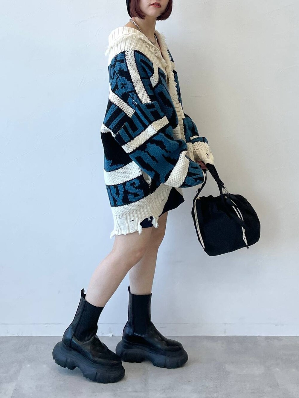 ブラック系のキャミソール、ブラック系のブーツ、ブルー系のスカートを着用したレディースの秋コーディネートの4枚目の写真