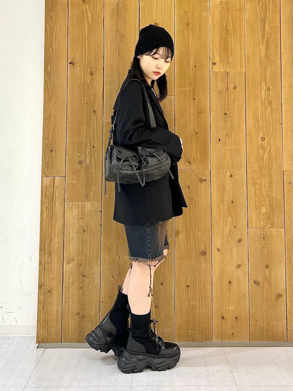 ブラック系のテーラードジャケット、ブラック系のショルダーバッグ、ブラック系のブーツを着用したレディースの秋コーディネートの4枚目の写真