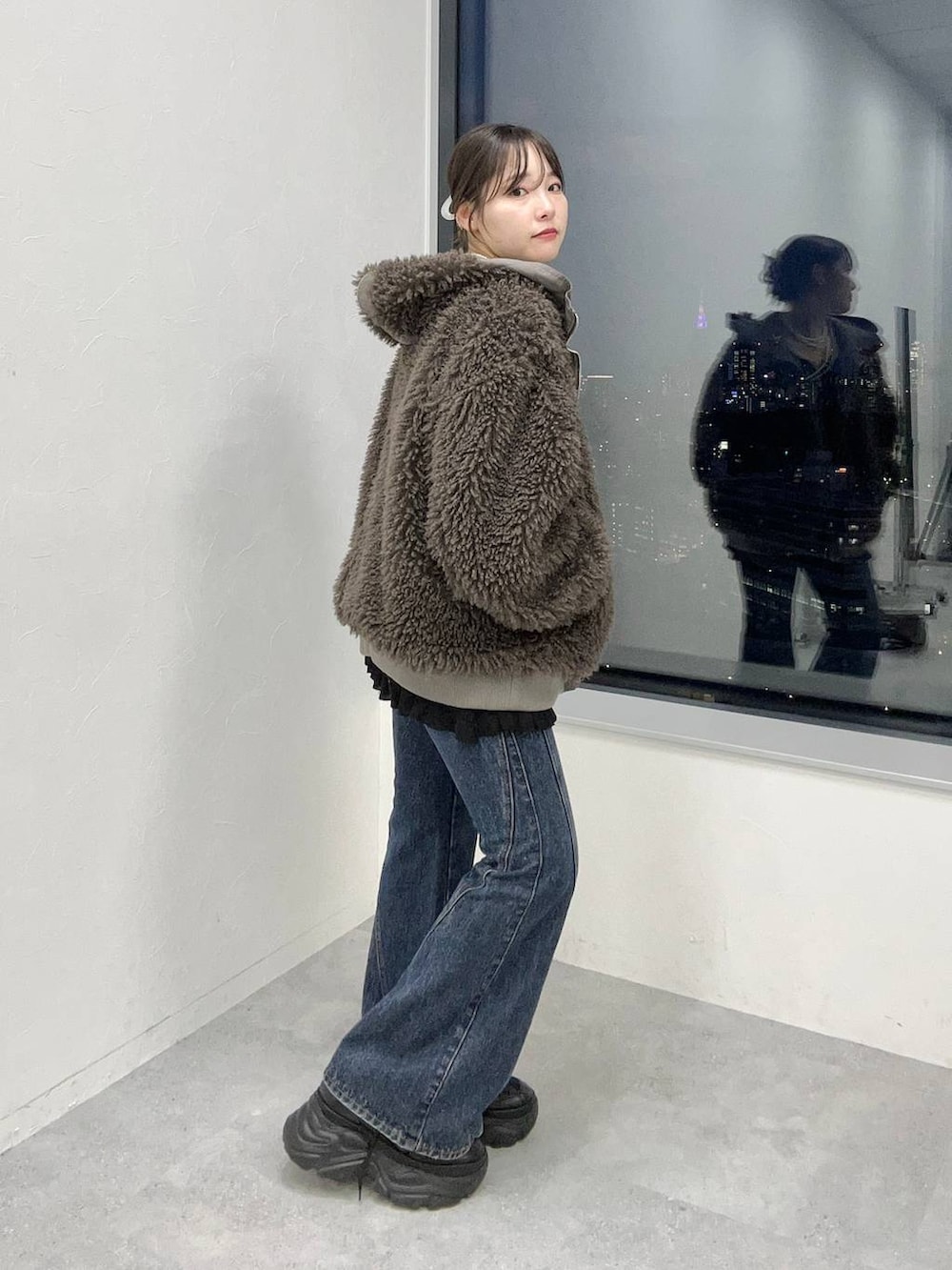 ブルー系のデニムパンツ、ブラウン系のブルゾンを着用したレディースの秋コーディネートの2枚目の写真