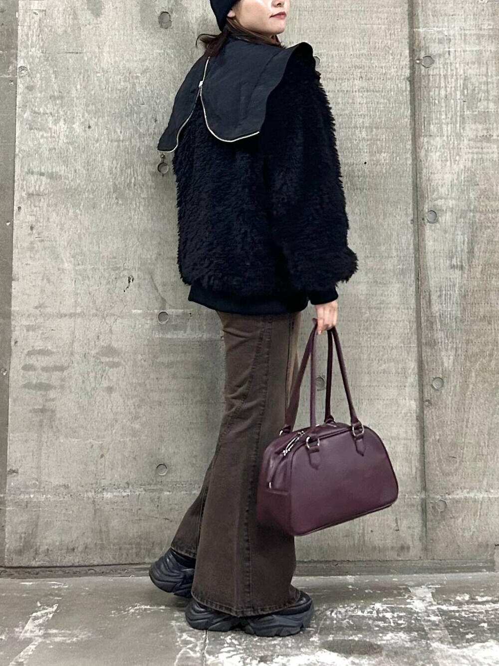 ブラウン系のデニムパンツ、ブラック系のブルゾン、ブラック系のボストンバッグを着用したレディースの秋コーディネートの4枚目の写真