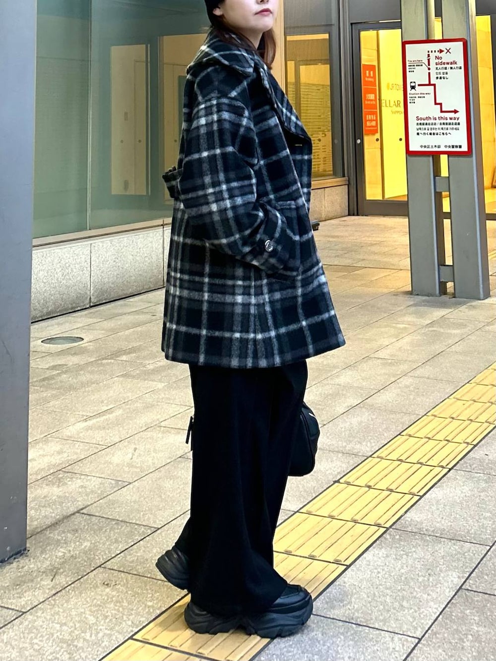 ブラック系のスニーカー、ブラック系のチェスターコート、ブラック系のボストンバッグを着用したレディースの秋コーディネートの4枚目の写真