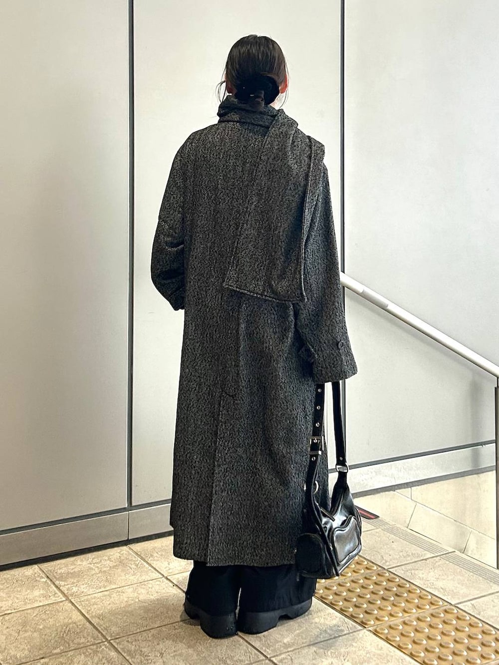 ブラック系のチェスターコート、ブラック系のスラックス、ブラック系のショルダーバッグを着用したレディースの冬コーディネートの8枚目の写真