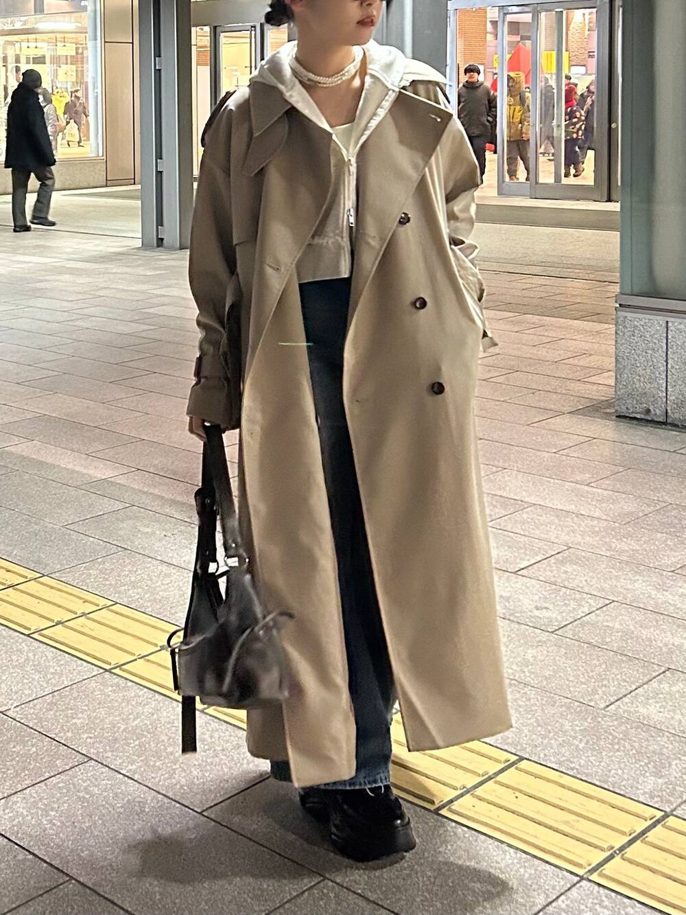 ブラック系のスニーカー、ブルー系のデニムパンツ、ブラック系のショルダーバッグを着用したレディースの春コーディネートの3枚目の写真