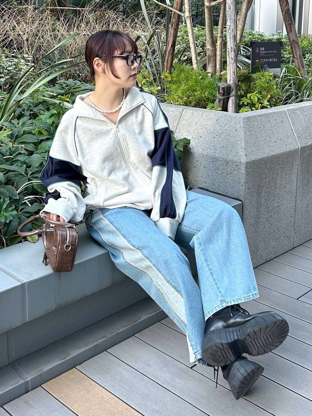 ブルー系のデニムパンツ、ブラウン系のボストンバッグ、ベージュ系のスウェットを着用したレディースの冬コーディネートの2枚目の写真