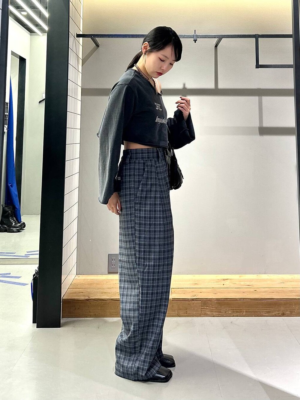 ブラック系のブーツ、グレー系のスラックス、ブラック系のハンドバッグを着用したレディースの秋コーディネートの3枚目の写真