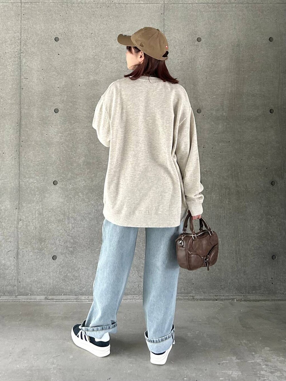 ベージュ系のスウェット、ブルー系のデニムパンツ、ブラック系のスニーカーを着用したレディースの春コーディネートの5枚目の写真