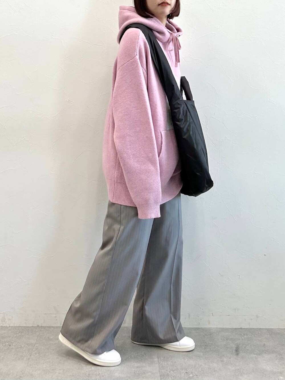 グレー系のスラックス、ブラック系のトートバッグ、ピンク系のニット/セーターを着用したレディースの冬コーディネートの5枚目の写真