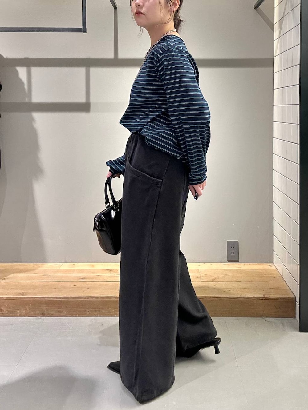 ブラック系のスウェットパンツ、ブラック系のショルダーバッグ、ブラック系のサンダルを着用したレディースの冬コーディネートの4枚目の写真