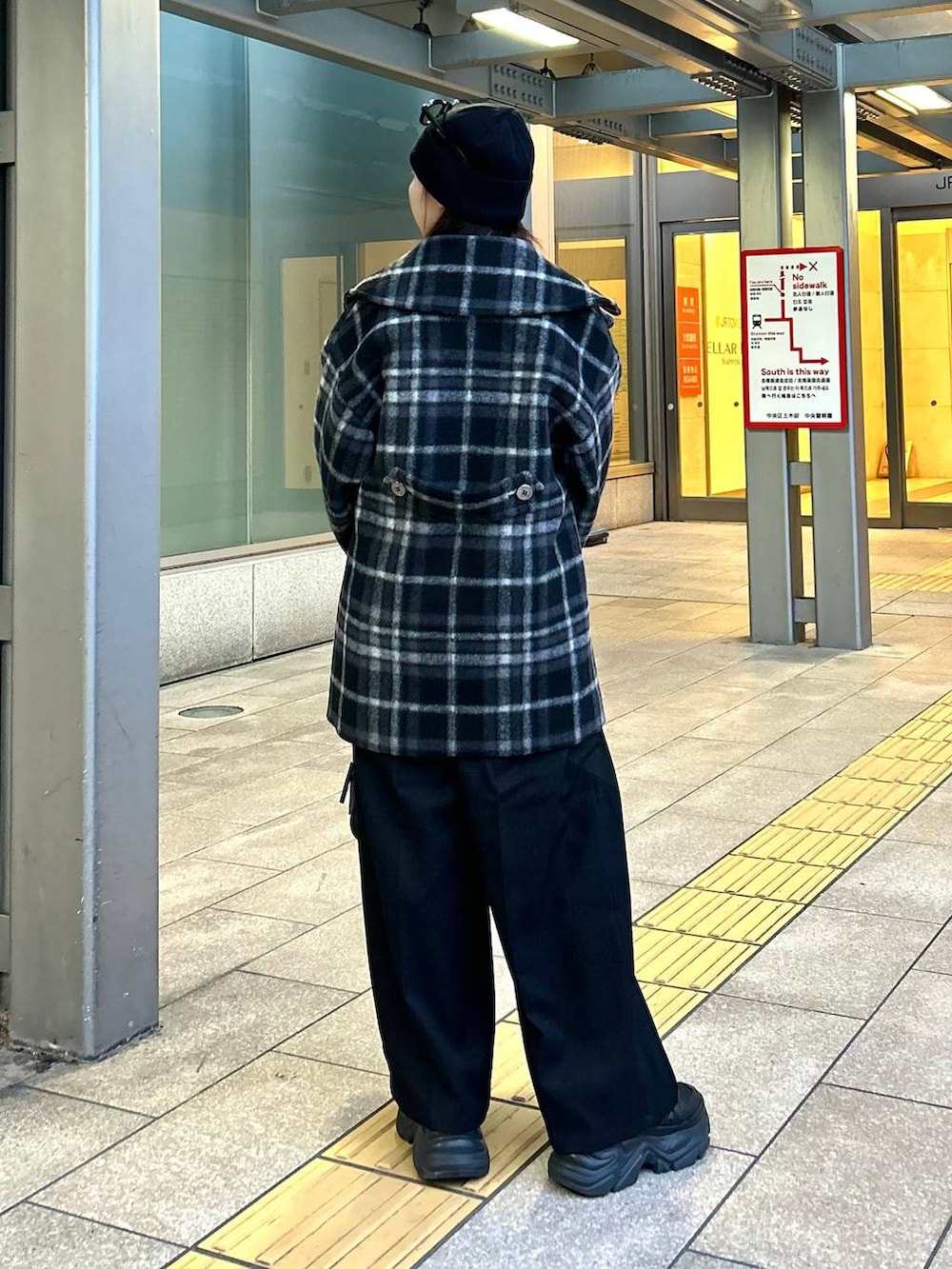 ブラック系のスニーカー、ブラック系のチェスターコート、ブラック系のボストンバッグを着用したレディースの秋コーディネートの5枚目の写真