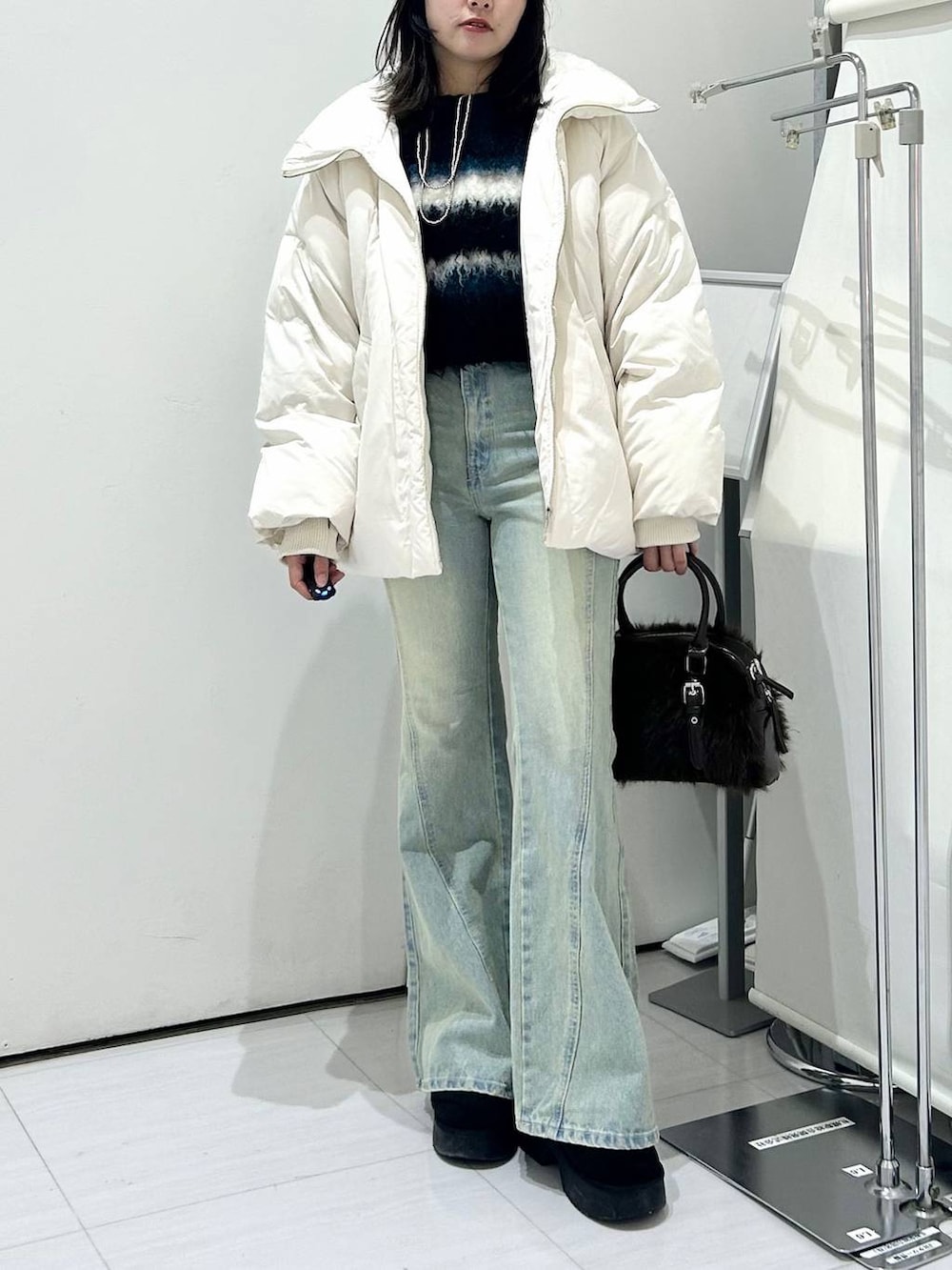 ブルー系のデニムパンツ、ホワイト系のブルゾン、ブラック系のブーツを着用したレディースの冬コーディネートの3枚目の写真