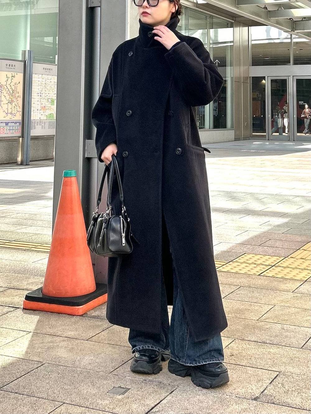 ブラック系のスニーカー、ブルー系のデニムパンツ、ブラック系のボストンバッグを着用したレディースの秋コーディネートの2枚目の写真