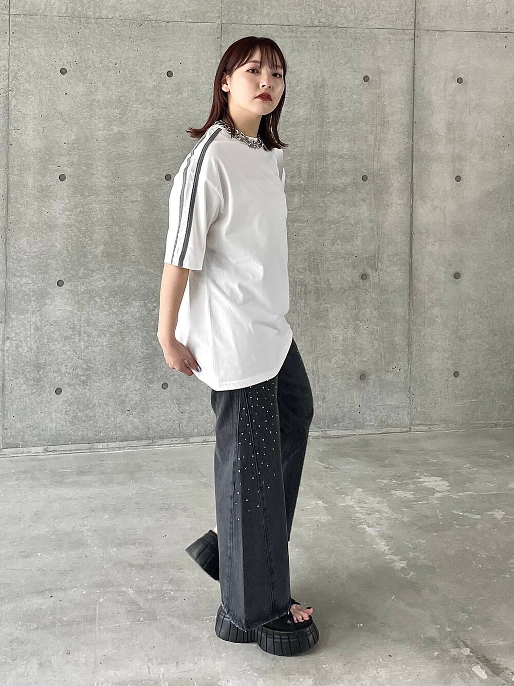 ブラック系のスニーカー、ホワイト系のTシャツ/カットソー、ブラック系のデニムパンツを着用したレディースの春コーディネートの5枚目の写真