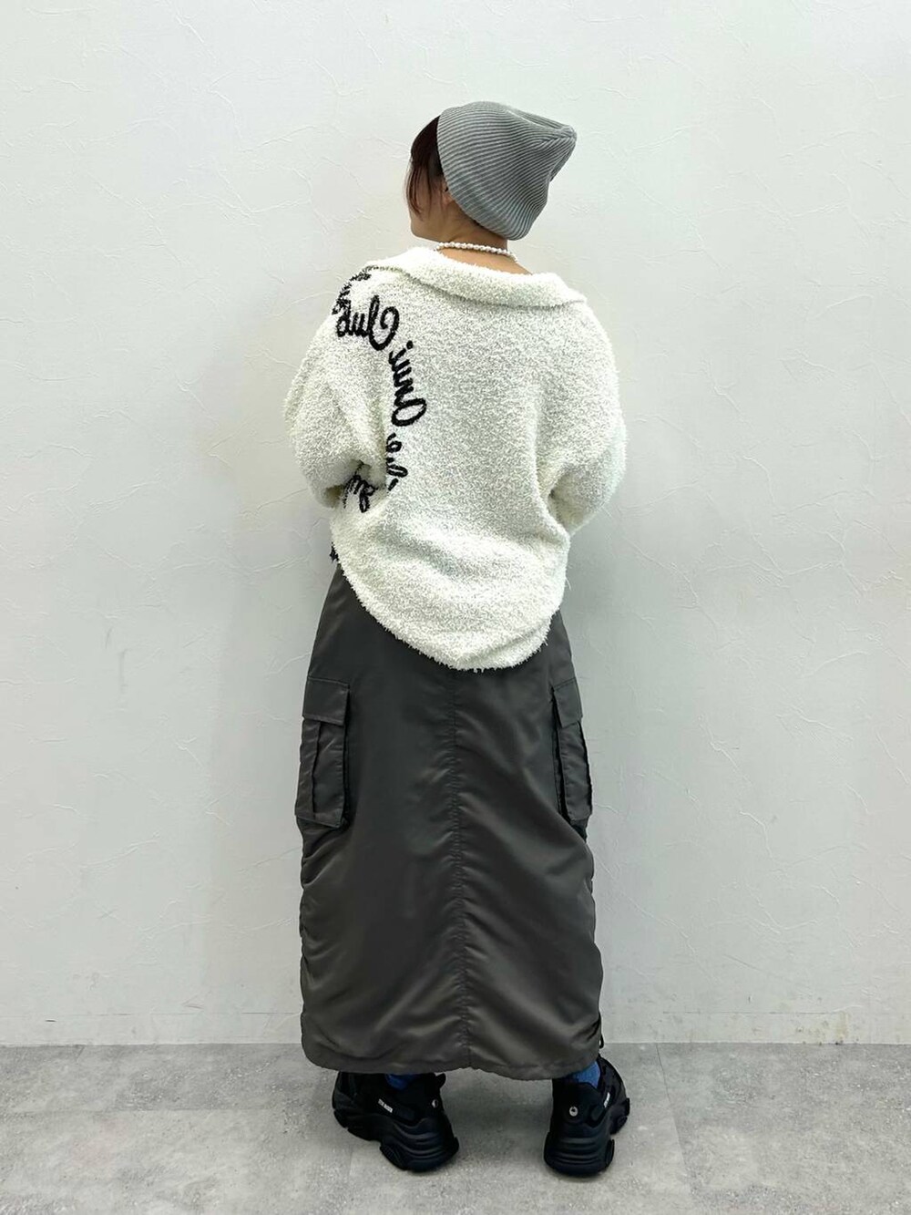 グレー系のスカート、ホワイト系のニット/セーターを着用したレディースの冬コーディネートの4枚目の写真