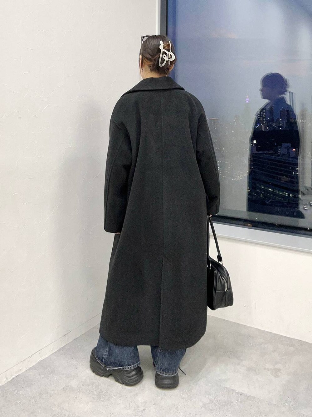 ブラック系のスニーカー、ブルー系のデニムパンツ、ブラック系のチェスターコートを着用したレディースの秋コーディネートの5枚目の写真