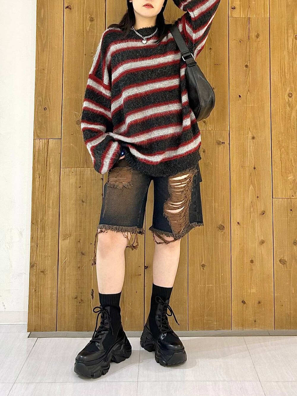 ブラック系のショルダーバッグ、ブラック系のブーツ、レッド系のニット/セーターを着用したレディースの秋コーディネートの3枚目の写真