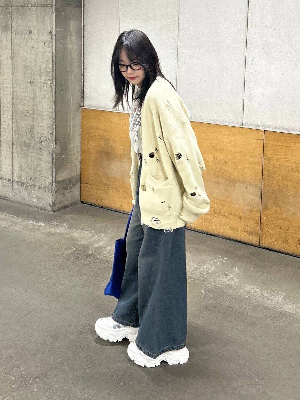 ホワイト系のスニーカー、ブルー系のデニムパンツ、ブルー系のトートバッグを着用したレディースの春コーディネートの3枚目の写真