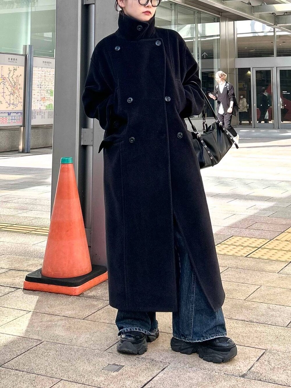 ブラック系のスニーカー、ブルー系のデニムパンツ、ブラック系のボストンバッグを着用したレディースの秋コーディネートの6枚目の写真