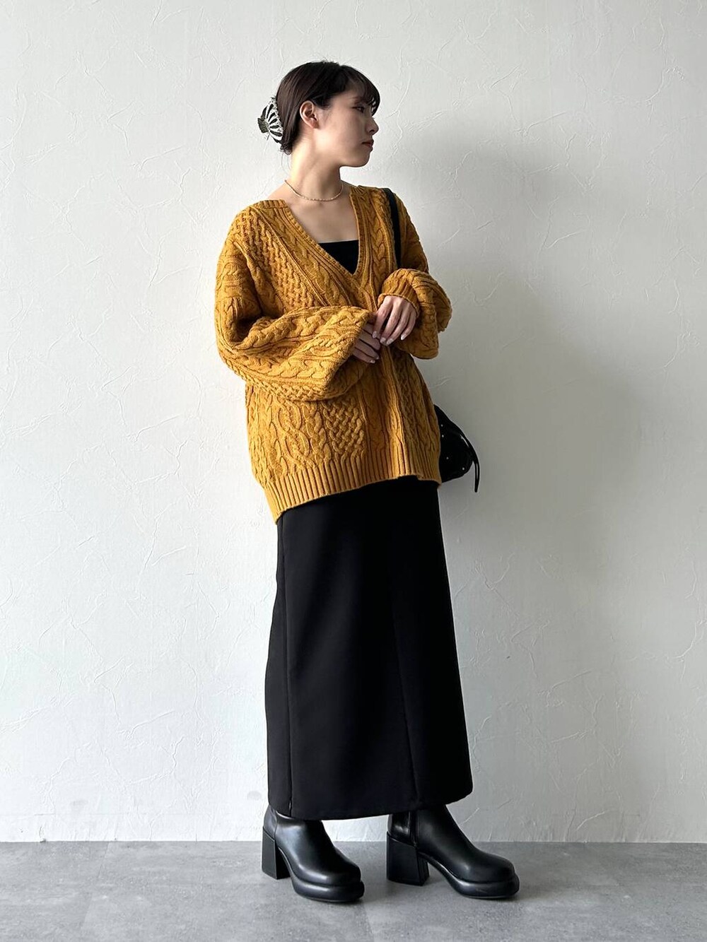 ブラック系のスカート、ブラック系のキャミソール、イエロー系のニット/セーターを着用したレディースの秋コーディネートの4枚目の写真