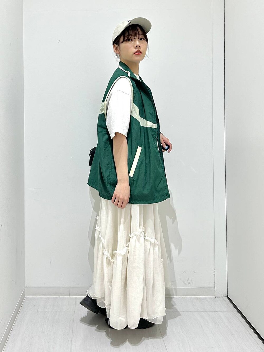 グリーン系のベスト、ホワイト系のスカート、ホワイト系のTシャツ/カットソーを着用したレディースの春コーディネートの4枚目の写真