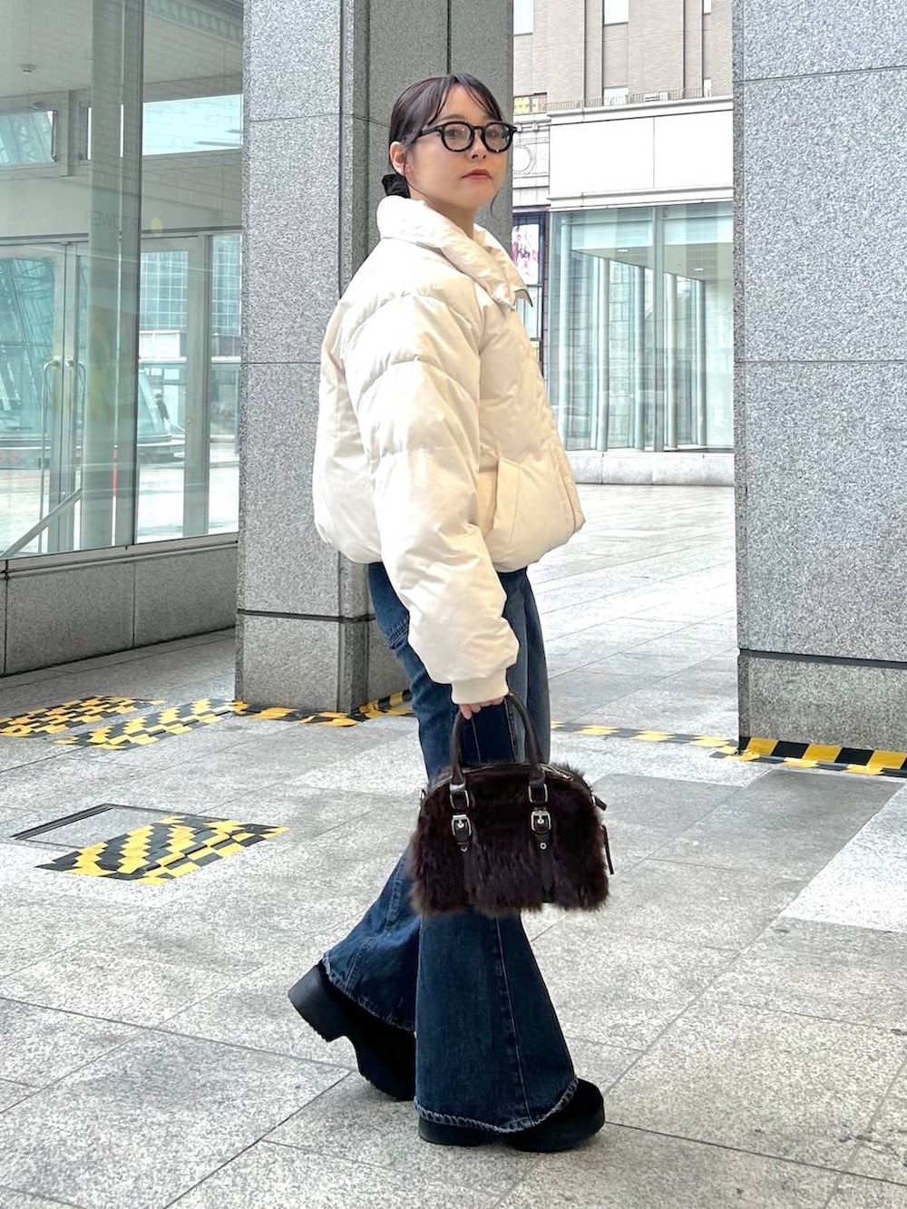 ブルー系のデニムパンツ、ホワイト系のブルゾン、ブラック系のブーツを着用したレディースの冬コーディネートの5枚目の写真