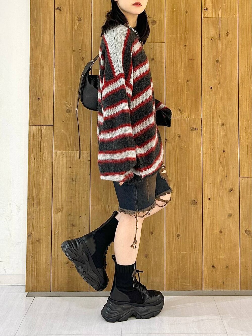 ブラック系のショルダーバッグ、ブラック系のブーツ、レッド系のニット/セーターを着用したレディースの秋コーディネートの5枚目の写真