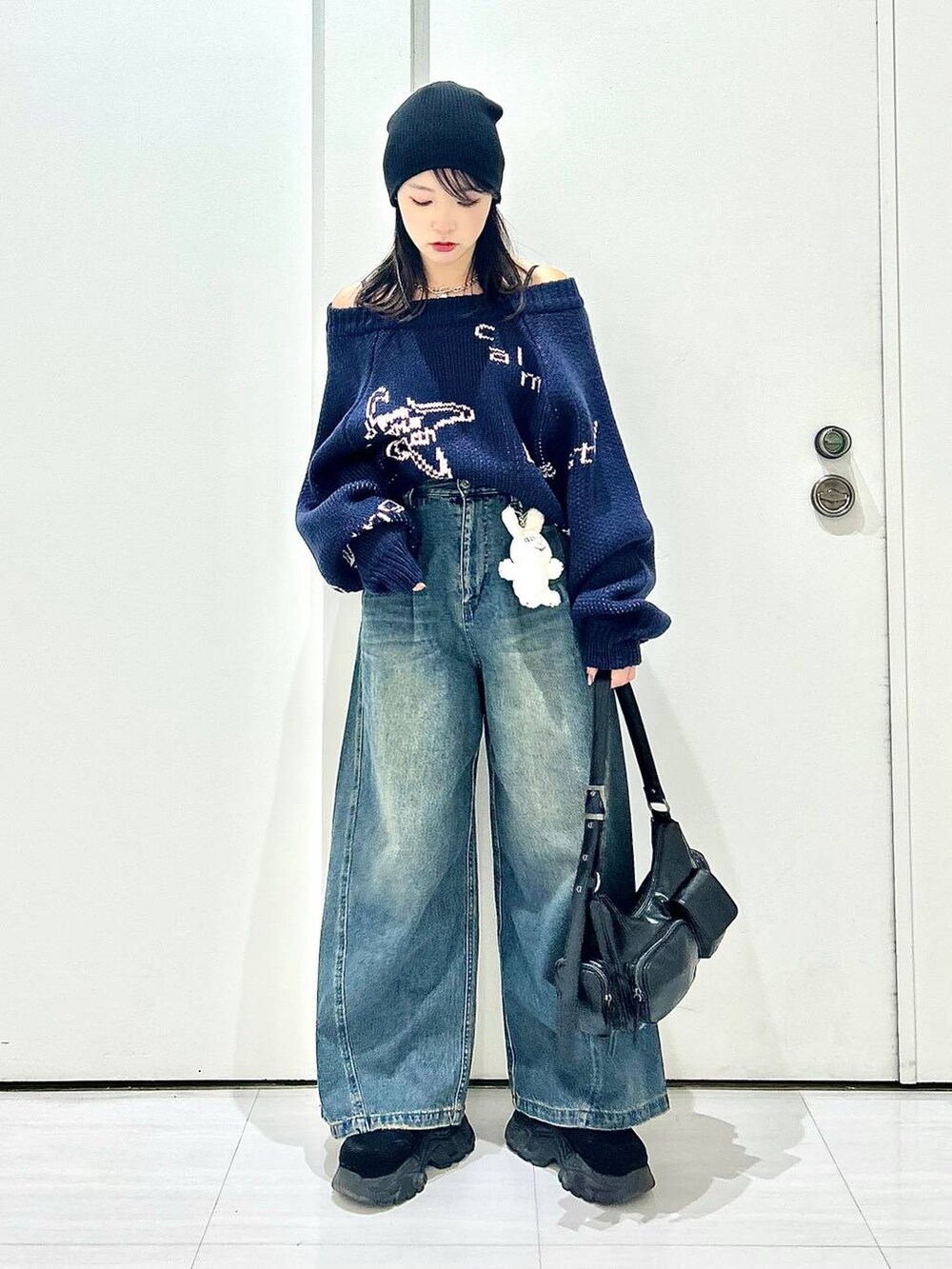 ブルー系のデニムパンツ、ブラック系のショルダーバッグ、ブルー系のニット/セーターを着用したレディースの秋コーディネートの2枚目の写真