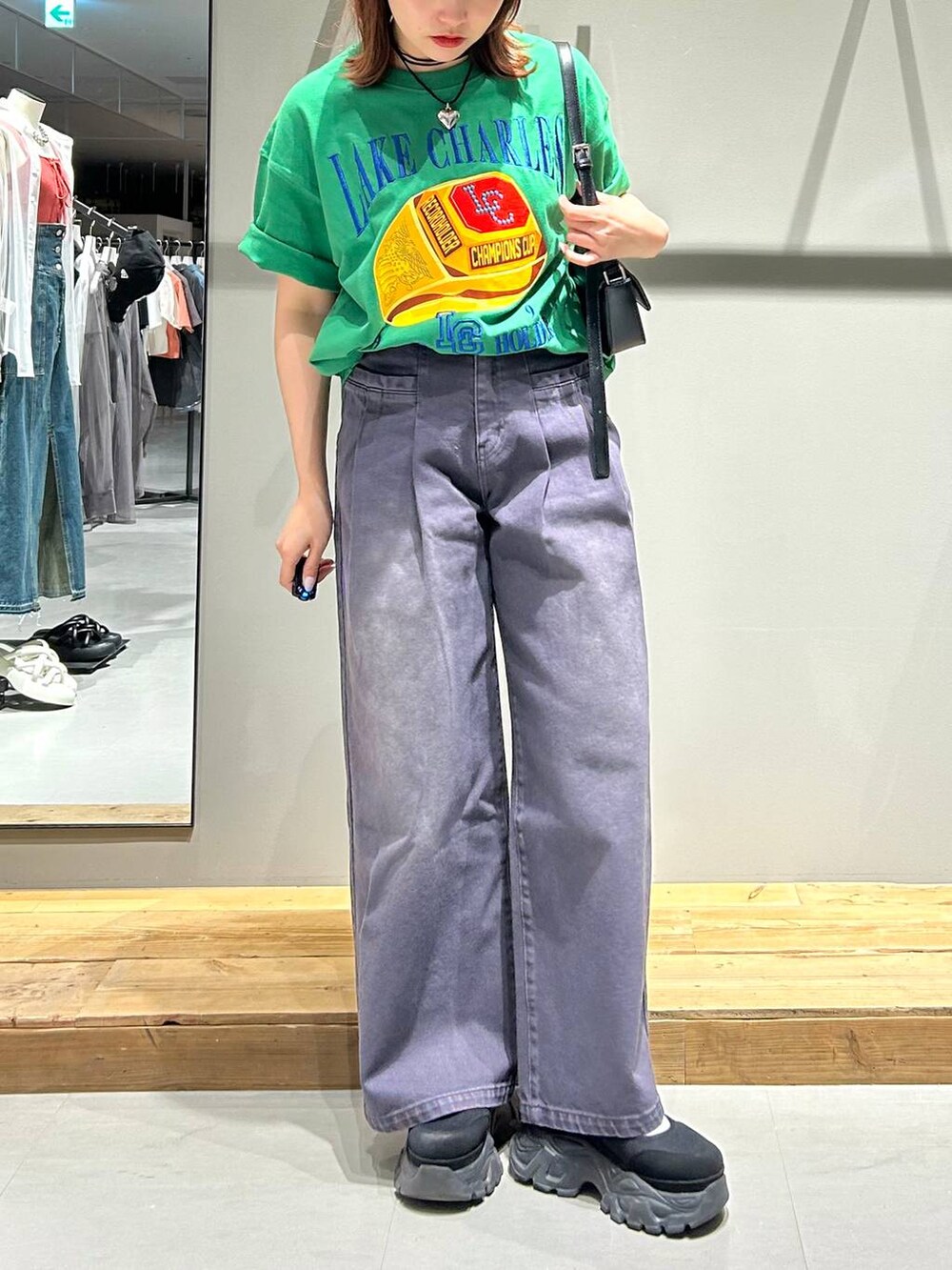 ブラック系のハンドバッグ、グリーン系のTシャツ/カットソー、ブラック系のデニムパンツを着用したレディースの春コーディネートの2枚目の写真