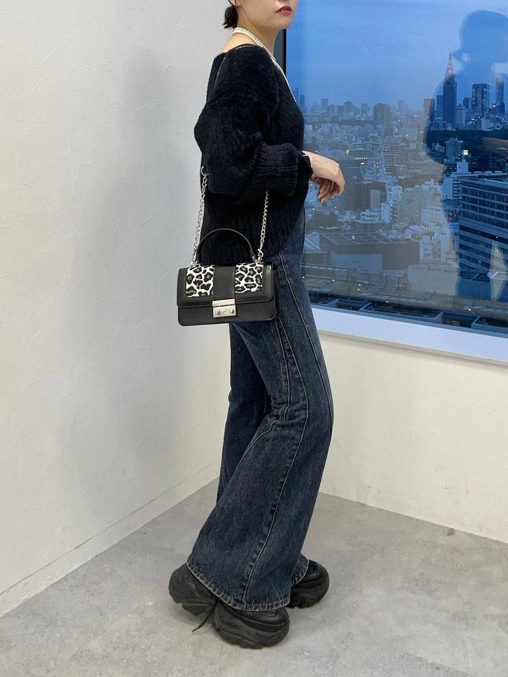 ブラック系のスニーカー、ブルー系のデニムパンツ、ブラック系のニット/セーターを着用したレディースの秋コーディネートの5枚目の写真