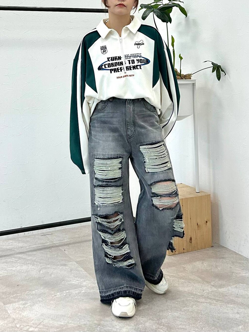 ホワイト系のポロシャツ、ブラック系のデニムパンツ、ブルー系のキャップを着用したレディースの冬コーディネートの2枚目の写真